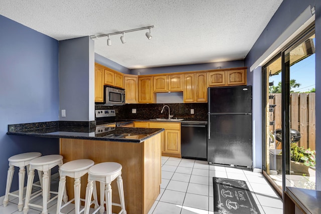 kitchen with sink, light tile patterned floors, backsplash, black appliances, and kitchen peninsula