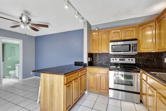 kitchen with light tile patterned flooring, stainless steel appliances, kitchen peninsula, and tasteful backsplash