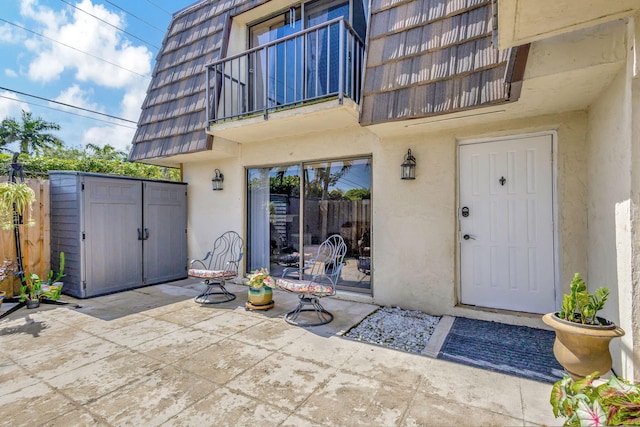 view of exterior entry featuring a patio area and a balcony