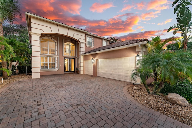 view of front of property with stucco siding, a garage, driveway, and a tile roof