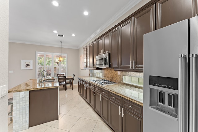 kitchen with a center island with sink, sink, hanging light fixtures, ornamental molding, and stainless steel appliances