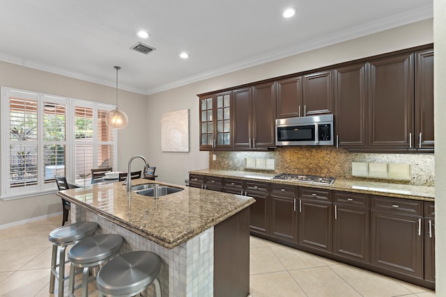 kitchen with backsplash, stainless steel appliances, light stone counters, and sink