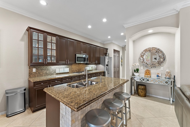 kitchen with sink, light tile patterned floors, ornamental molding, appliances with stainless steel finishes, and dark brown cabinetry