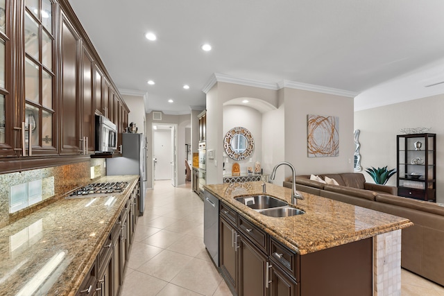 kitchen featuring a kitchen island with sink, sink, ornamental molding, light stone counters, and stainless steel appliances