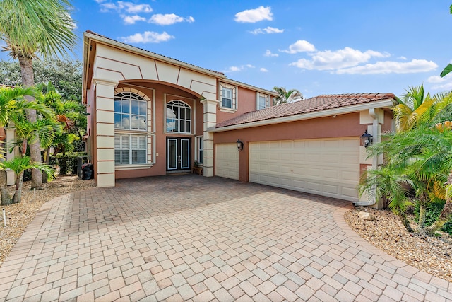 view of front of home with stucco siding, a tiled roof, decorative driveway, and a garage