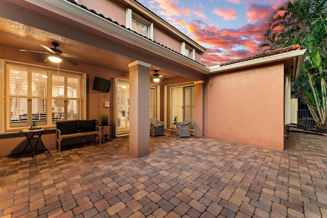 patio terrace at dusk with outdoor lounge area and ceiling fan