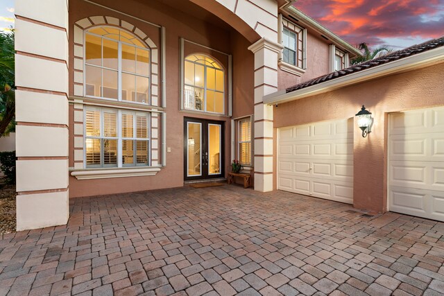 exterior entry at dusk with french doors and a garage