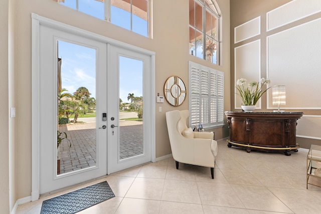 doorway with french doors, a towering ceiling, a healthy amount of sunlight, and light tile patterned flooring