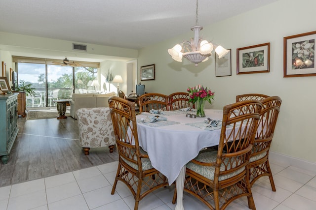 tiled dining area with a textured ceiling and a chandelier