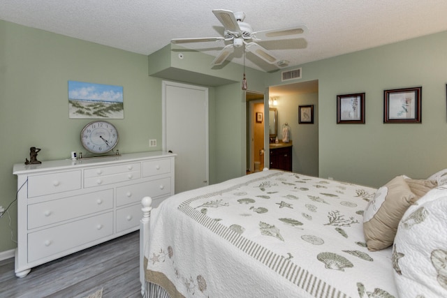 bedroom with ceiling fan, dark hardwood / wood-style floors, and a textured ceiling