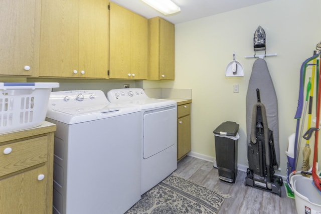 washroom with cabinets, light wood-type flooring, and washing machine and dryer