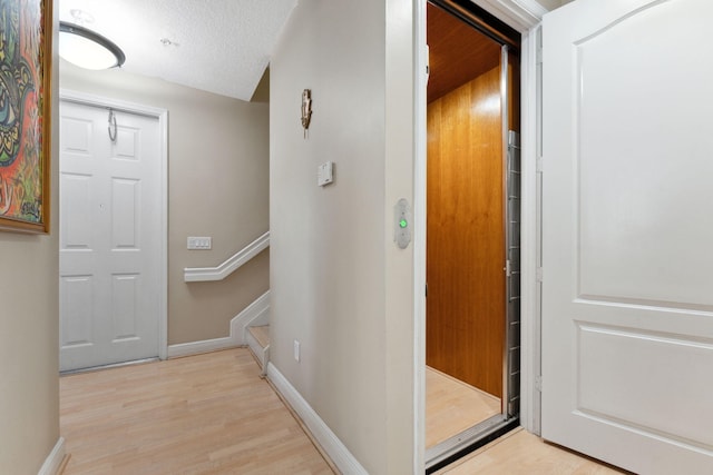 hall featuring a textured ceiling and light hardwood / wood-style flooring