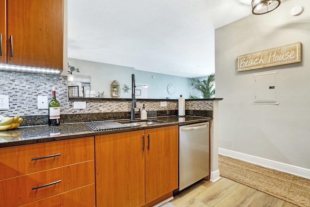 kitchen featuring dark stone counters, sink, stainless steel dishwasher, light hardwood / wood-style floors, and tasteful backsplash