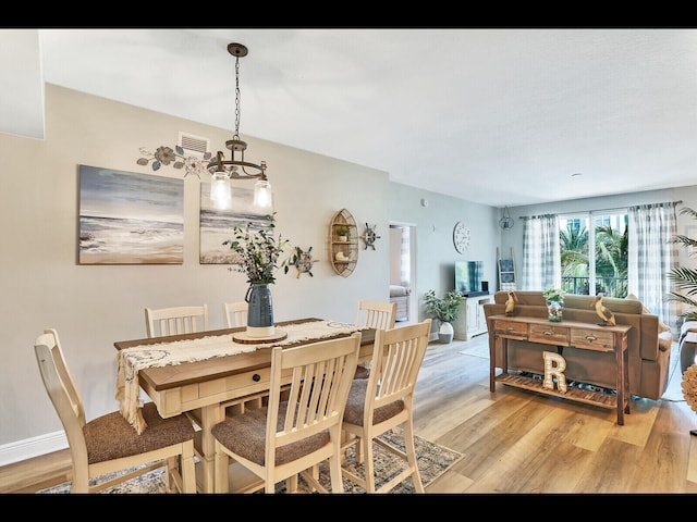 dining area with light hardwood / wood-style floors and a notable chandelier