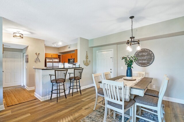 dining area with light hardwood / wood-style flooring and rail lighting