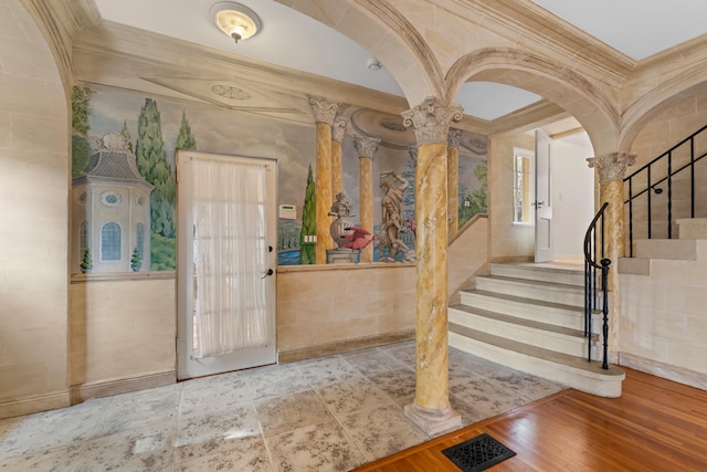 entrance foyer featuring light wood-type flooring, crown molding, and decorative columns