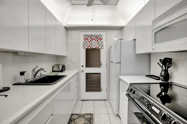 kitchen featuring tasteful backsplash, sink, light tile patterned floors, white cabinets, and black electric range oven