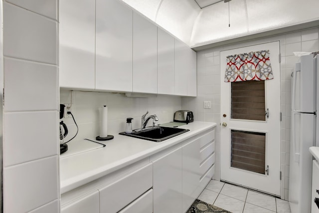 kitchen featuring white cabinets, white fridge, light tile patterned floors, and sink