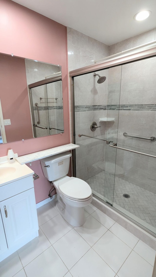 bathroom featuring tile patterned flooring, toilet, a shower with door, and vanity