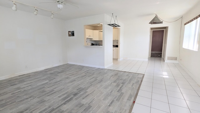 unfurnished living room with ceiling fan, rail lighting, and light hardwood / wood-style flooring