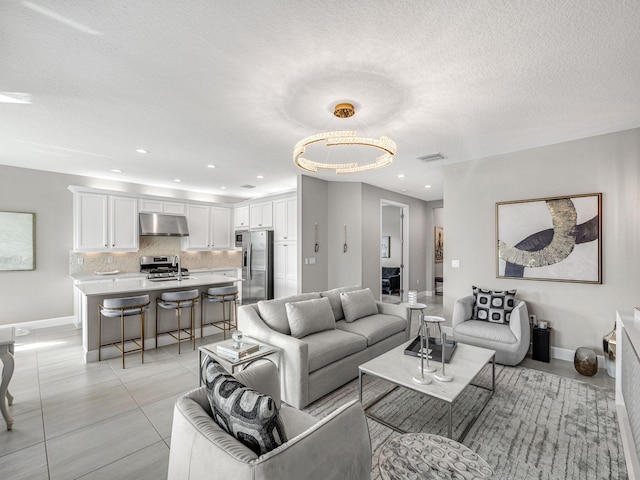 tiled living room featuring a notable chandelier, a textured ceiling, and sink