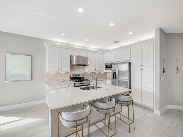 kitchen featuring sink, white cabinetry, a kitchen bar, and stainless steel appliances