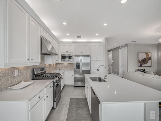 kitchen featuring appliances with stainless steel finishes, sink, white cabinets, range hood, and a center island with sink