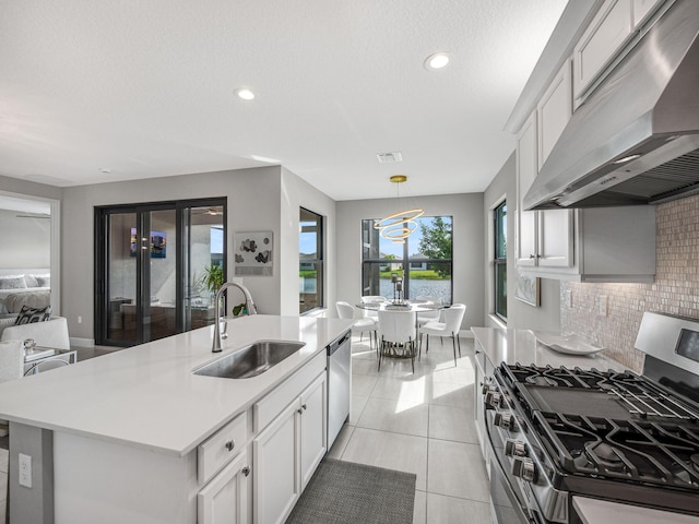 kitchen with a center island with sink, light tile patterned floors, backsplash, stainless steel appliances, and sink