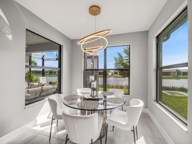 tiled dining room featuring a water view, a notable chandelier, and plenty of natural light