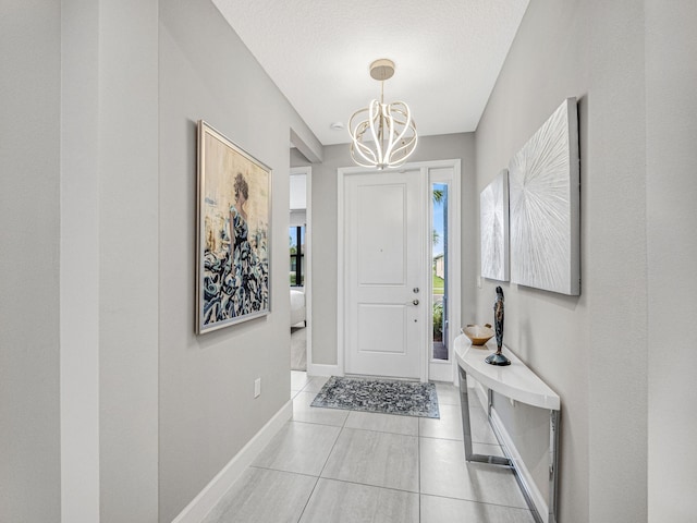 foyer entrance with a textured ceiling, light tile patterned floors, and a chandelier