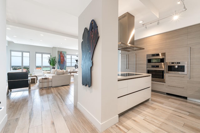 kitchen with track lighting, double oven, light hardwood / wood-style floors, and range hood