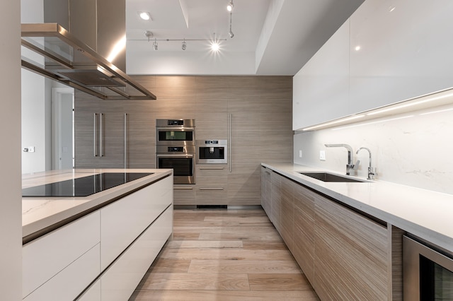 kitchen featuring light hardwood / wood-style floors, beverage cooler, black electric cooktop, sink, and double oven