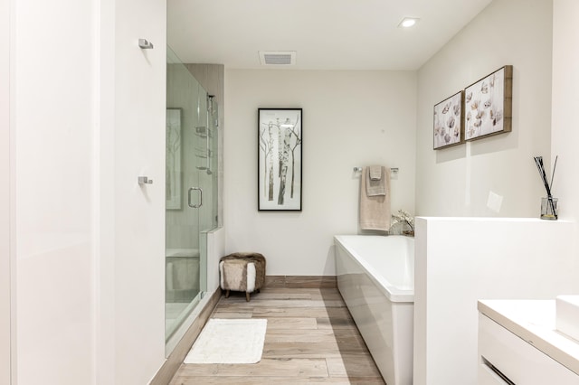 bathroom with wood-type flooring, vanity, and shower with separate bathtub