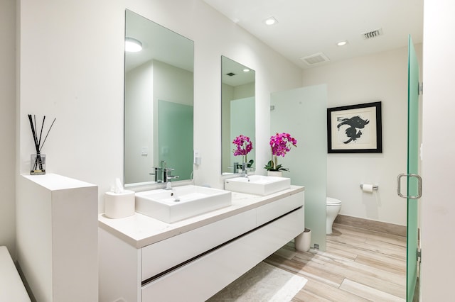 bathroom featuring vanity, toilet, a shower with door, and hardwood / wood-style flooring