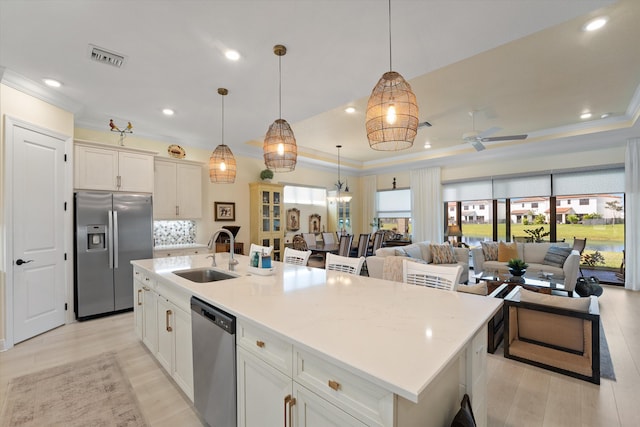 kitchen featuring appliances with stainless steel finishes, sink, pendant lighting, and an island with sink