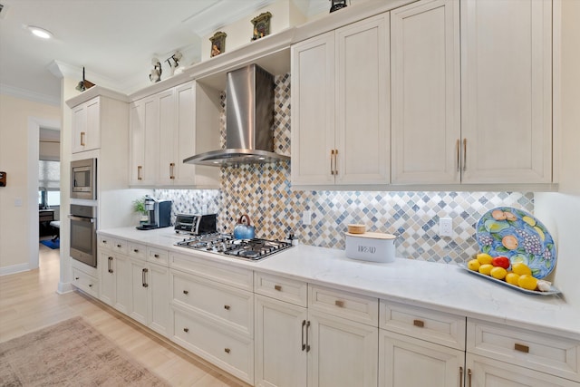 kitchen featuring appliances with stainless steel finishes, backsplash, wall chimney exhaust hood, light stone counters, and ornamental molding