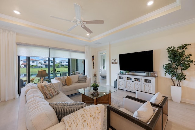 living room featuring ornamental molding, light hardwood / wood-style flooring, a tray ceiling, and ceiling fan