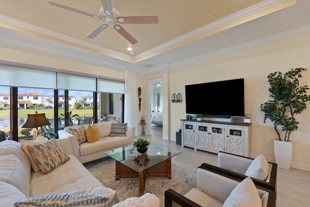 living room with ceiling fan, a tray ceiling, ornamental molding, and light hardwood / wood-style flooring