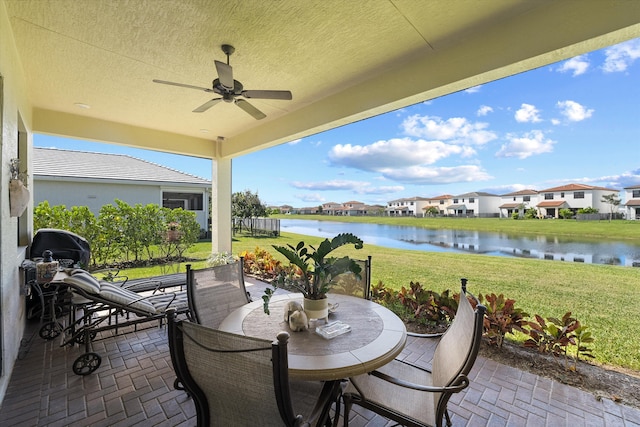 view of patio with a water view and ceiling fan