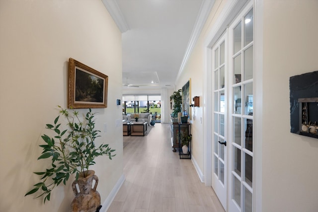 hallway with french doors, crown molding, and light wood-type flooring