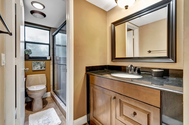 bathroom featuring a shower with shower door, vanity, and toilet