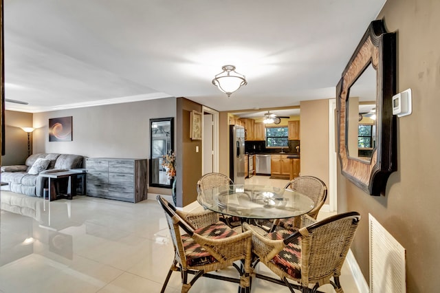 tiled dining area featuring ornamental molding and ceiling fan