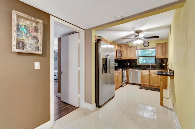 kitchen with ceiling fan, sink, decorative backsplash, appliances with stainless steel finishes, and light tile patterned floors