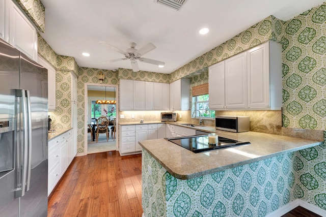 kitchen with light hardwood / wood-style floors, kitchen peninsula, stainless steel appliances, and sink