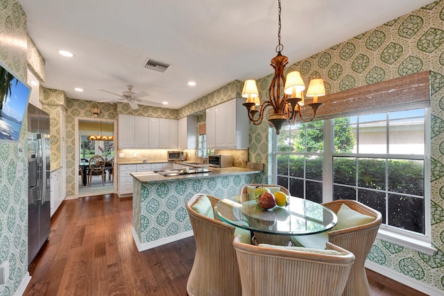 kitchen with dark hardwood / wood-style floors, kitchen peninsula, sink, white cabinets, and ceiling fan with notable chandelier