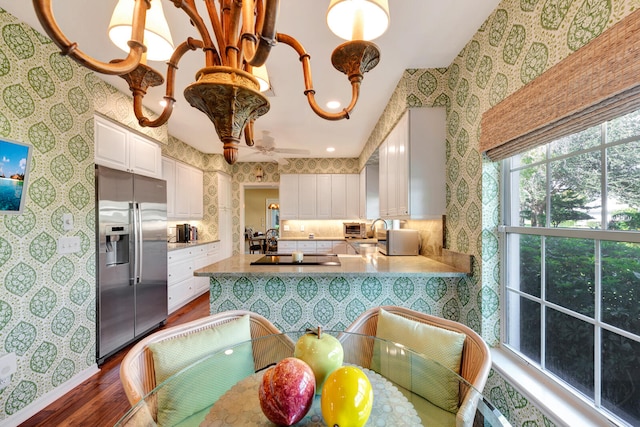 kitchen with kitchen peninsula, dark hardwood / wood-style flooring, white cabinetry, stainless steel refrigerator with ice dispenser, and decorative light fixtures