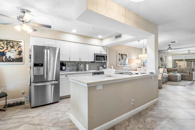 kitchen with appliances with stainless steel finishes, a textured ceiling, sink, and white cabinets