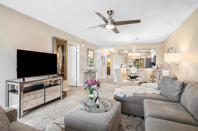 living room featuring ceiling fan with notable chandelier and a textured ceiling