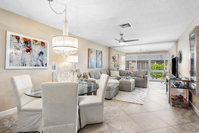 dining area with ceiling fan with notable chandelier and a textured ceiling