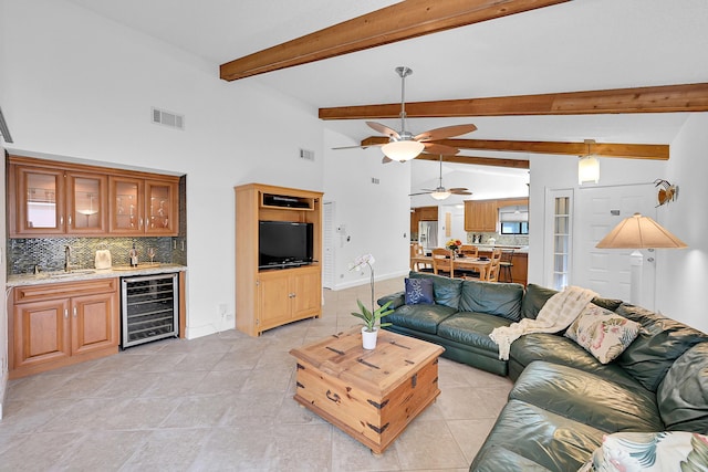 living room with wine cooler, beam ceiling, sink, and high vaulted ceiling